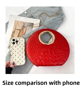 Red crocodile embossed round handbag size comparison with a phone and gold handle