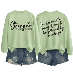 Detailed front and back view of green sweatshirt with Stronger Than The Storm print