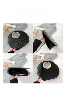 Detail of black faux crocodile leather handbag with elegant gold metal ring and chain strap