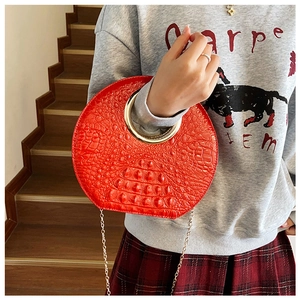 Detail of red crocodile pattern handbag with gold ring handle and chain strap