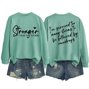 Detailed front and back view of mint green sweatshirt with Stronger than the Storm print