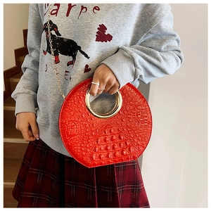 Red crocodile texture handbag with golden ring handle and chain strap on a model