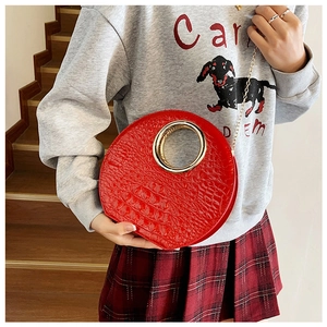 Detail of red crocodile texture bag with gold metal handle and chain shoulder strap