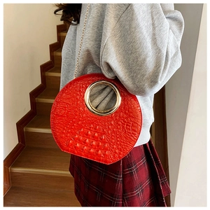 Detail of red croc-embossed handbag with gold metal ring handle and chain strap
