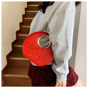 Macro detail of red crocodile embossed handbag with golden ring handle and chain strap