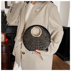 Detail of black crocodile texture bag with large gold metal ring handle and chain