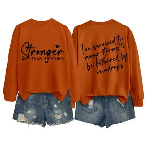 Detail view of orange sweatshirt with printed text and distressed denim shorts set