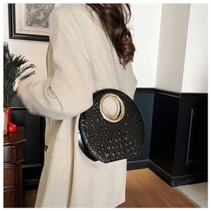 Chic black crocodile texture bag with gold ring handle and chain strap on a model