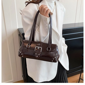 Détail d'un sac à main en cuir brillant marron foncé avec boucle argentée et rivets