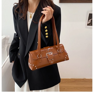 Détail d'un sac en cuir marron brillant avec des rivets argentés et une boucle