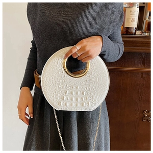 Detail of white round cloud bag with crocodile texture and golden metal ring handle
