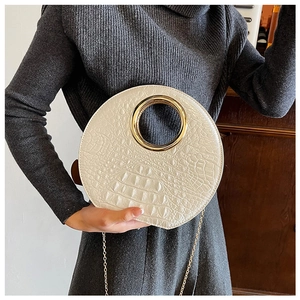 Close-up of off-white crocodile embossed round handbag with gold metal handle and chain