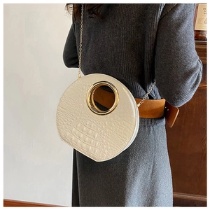 Detail view of white crocodile pattern round bag with large gold metal ring handle