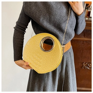 Detail of yellow crocodile embossed clutch with large gold metal ring handle and chain