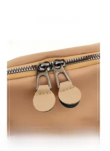 Close-up of dual smooth metal zippers with leather pullers on a casual crossbody bag