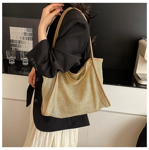Détail du sac cabas en maille tissée avec anses en cuir marron porté par un mannequin