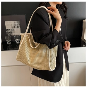 Détail d'un sac cabas en paille tissée avec bandoulières en cuir blanc porté par un mannequin