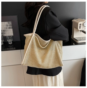 Detail showing natural woven straw texture and contrast white leather trim on tote bag