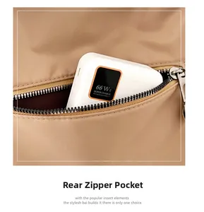 Detail of rear zipper pocket on brown nylon crossbody bag with power bank storage