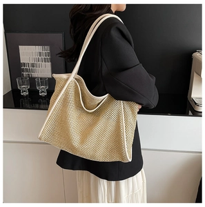 Gros plan d'un sac cabas tissé beige avec bordure contrastée et bandoulière longue