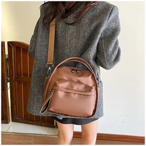 Detailed back view of a brown multi-layer nylon crossbody bag worn with a wool coat