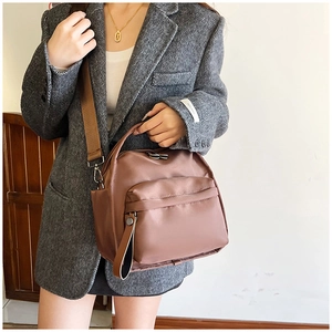 Detail of milk tea brown nylon crossbody bag with wide strap on grey blazer