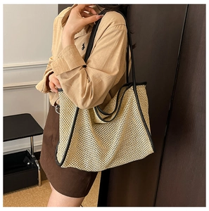 Détail d'un grand sac cabas tissé beige avec bandoulières en cuir noir style rétro
