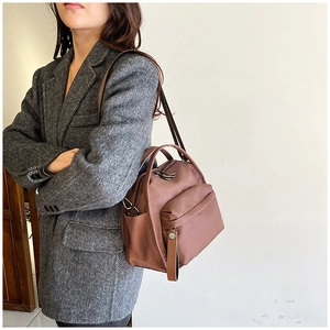 Detailed view of a brown multi-layer crossbody bag on a model in a grey blazer