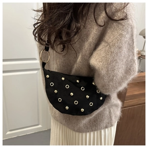 Detailed view of black suede shoulder bag featuring golden rivets and eyelet decorations