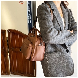 Detailed view of brown nylon crossbody bag featuring wide front zipper and side storage pockets