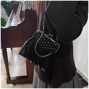 Close-up of black fringe shoulder bag with metal rivet accents and kiss-lock closure
