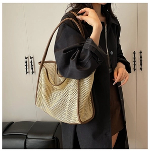 Détail du sac cabas en paille tissé avec bordure en cuir marron porté par un mannequin