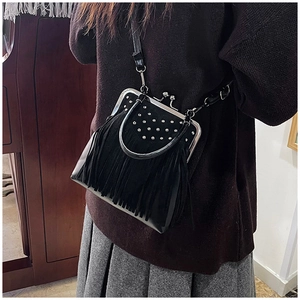Dettaglio della borsa a tracolla in camoscio nero con frange e borchie su una modella