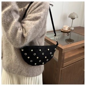 Close-up of suede shoulder bag featuring gold studs and metal eyelet details on a black finish