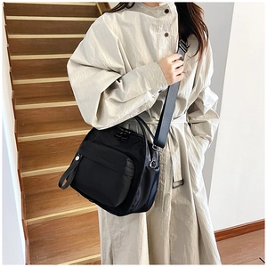 Waterproof black nylon shoulder bag with wide woven strap shown on a model