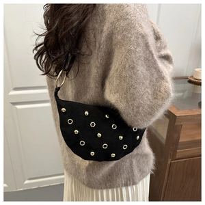 Detail of black suede hobo bag with gold studs and large ring handle worn by a model