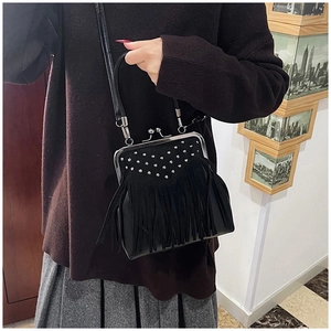 Detailed view of a black fringe crossbody bag with silver studs and metal clasp closure