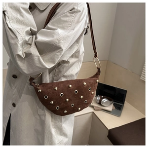 Close-up of brown suede moon bag featuring gold metallic rivets and eyelet details