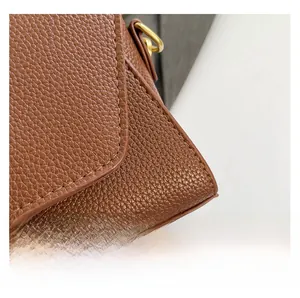 Dettaglio borsa in pelle marrone motivo litchi con cuciture e anello in metallo oro