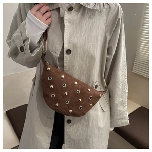 Detail of vintage brown suede crescent bag featuring golden rivets and a wide shoulder strap