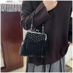 Detail of black kiss-lock bag with silver rivets, fringe accents and leather handle