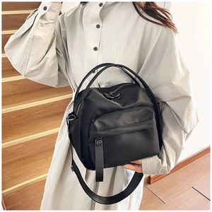 Detail of black waterproof nylon crossbody bag with dual handles and wide shoulder strap
