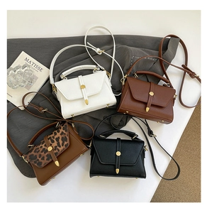Detail view of lychee grain leather bags in various colors with gold cylinder hardware