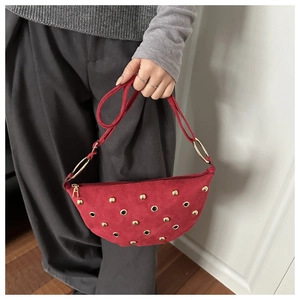 Detail of red suede crescent bag with gold metal studs and ring hardware detail