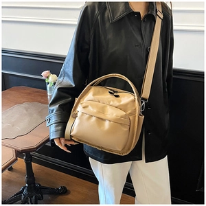 Fashionable khaki nylon multi-layer crossbody bag worn by a model in a minimalist setting