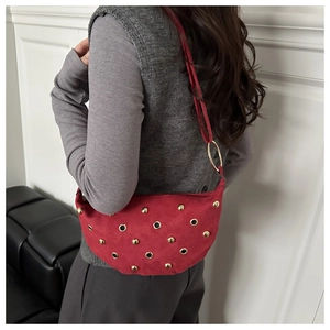 Detail of red suede hobo bag featuring golden rivets and eyelets with shoulder strap