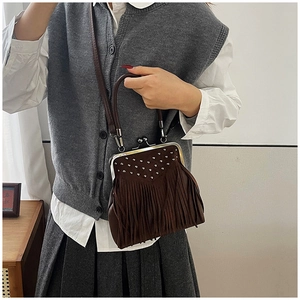 Detail of dark brown crossbody bag with silver rivets and long tassel decorations