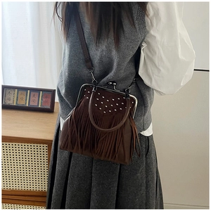Detail of vintage brown tassel handbag featuring silver studs and metal clasp closure
