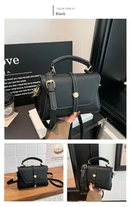 Detailed view of black pebbled leather crossbody bag with gold round metal buckle