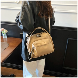 Beige nylon crossbody bag with adjustable strap shown in a minimalist indoor setting